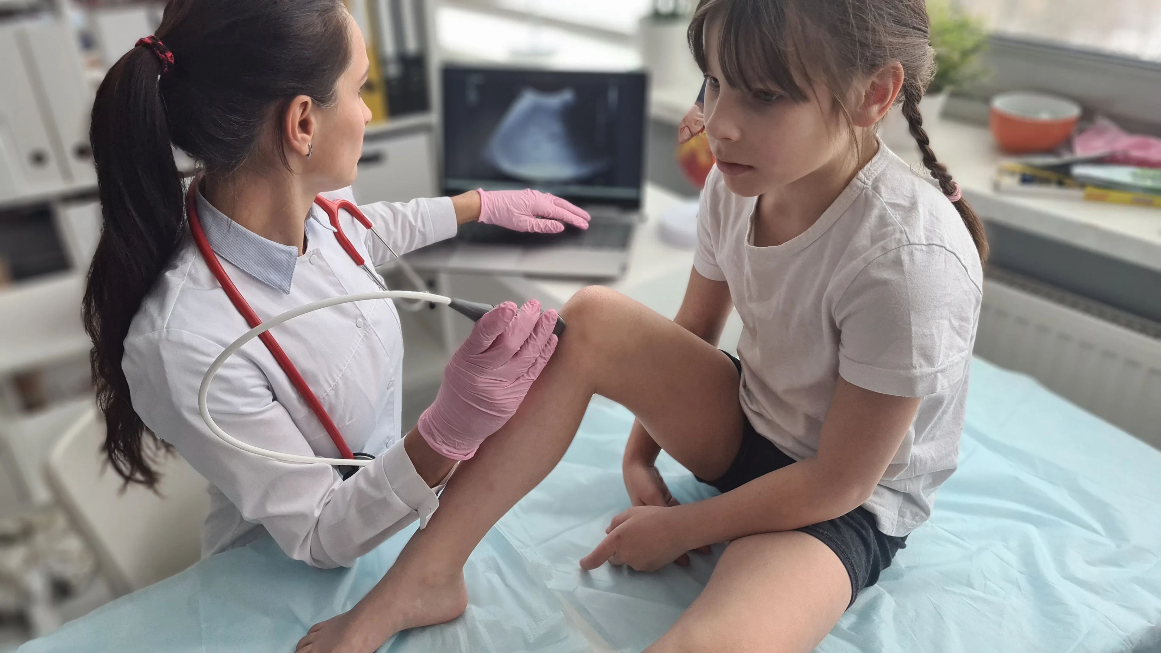 Doctor examining child's knee with ultrasound.