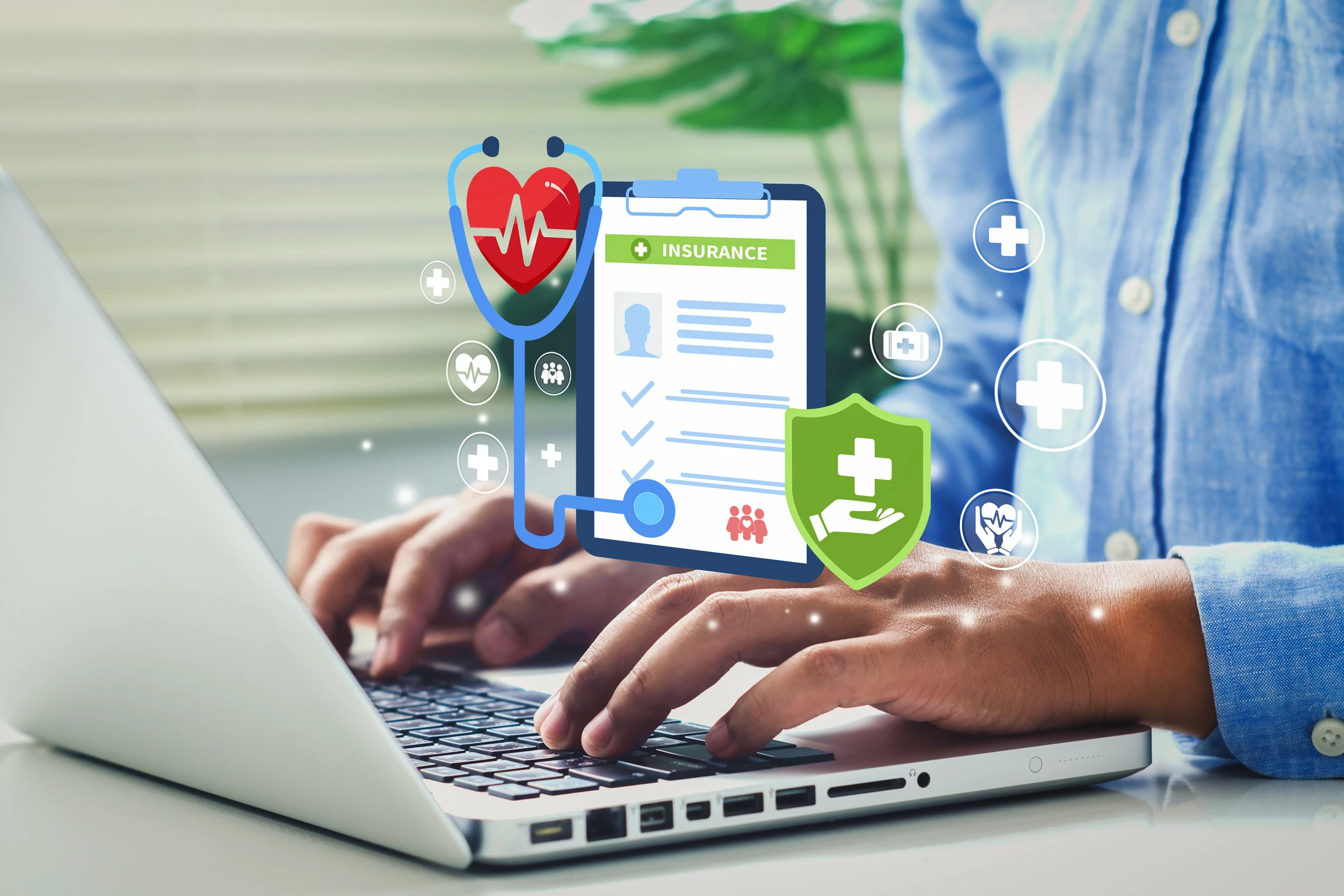 Typing on laptop with health insurance icons.