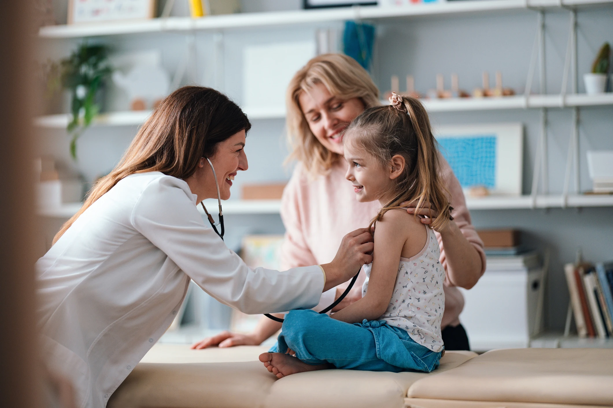 Doctor examining smiling girl with stethoscope.