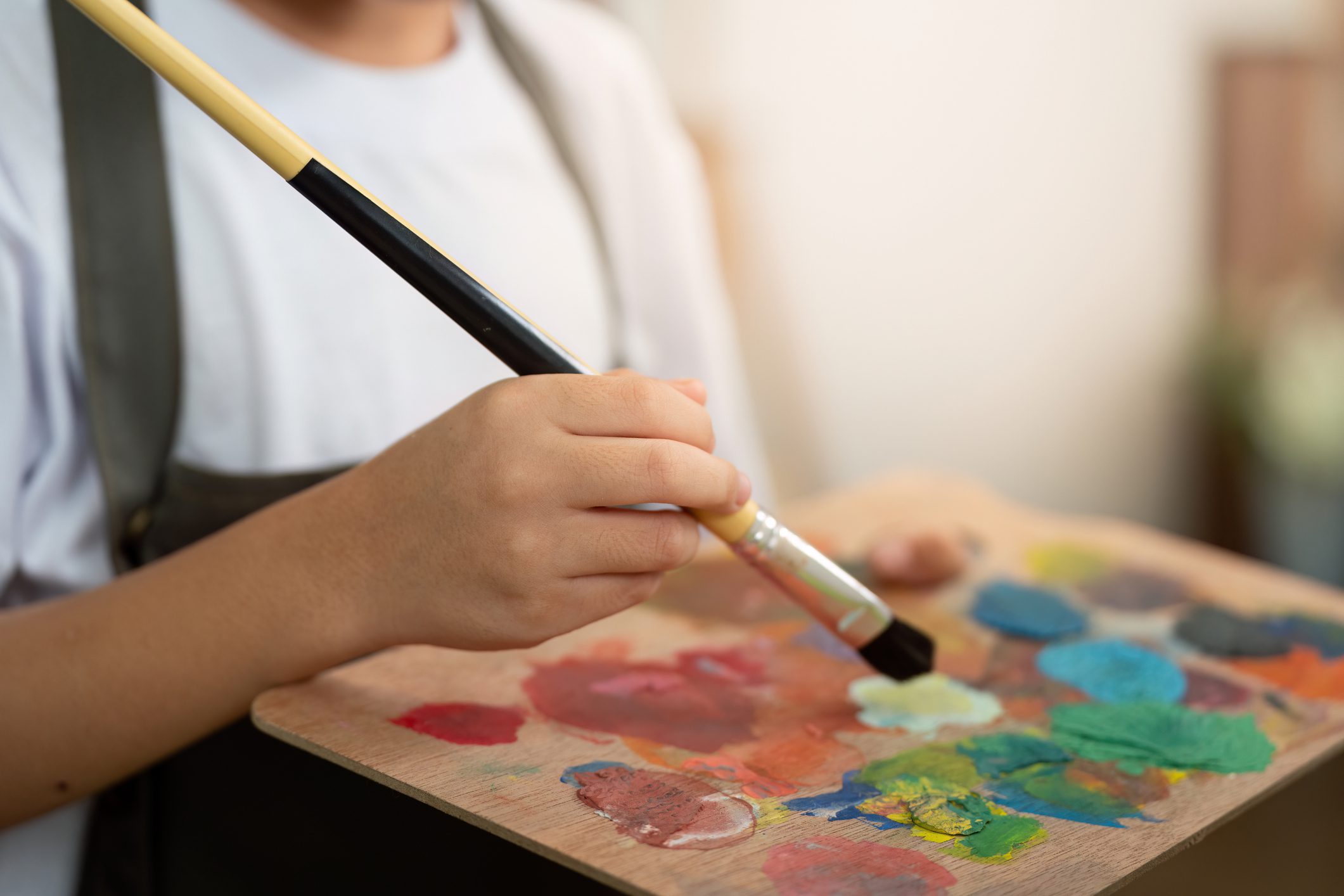 Person painting with colorful palette and brush.