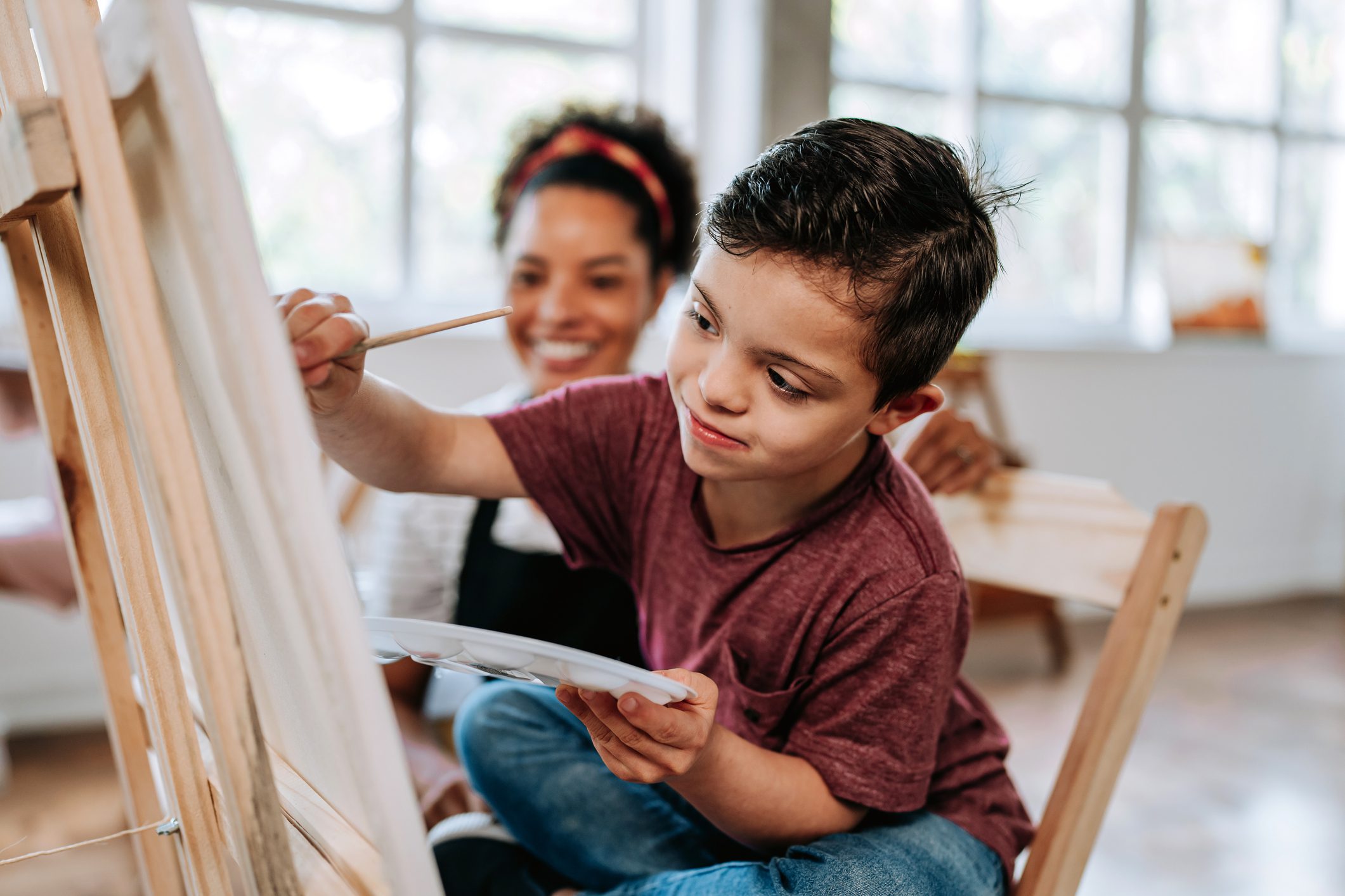 Child painting with a teacher's guidance.