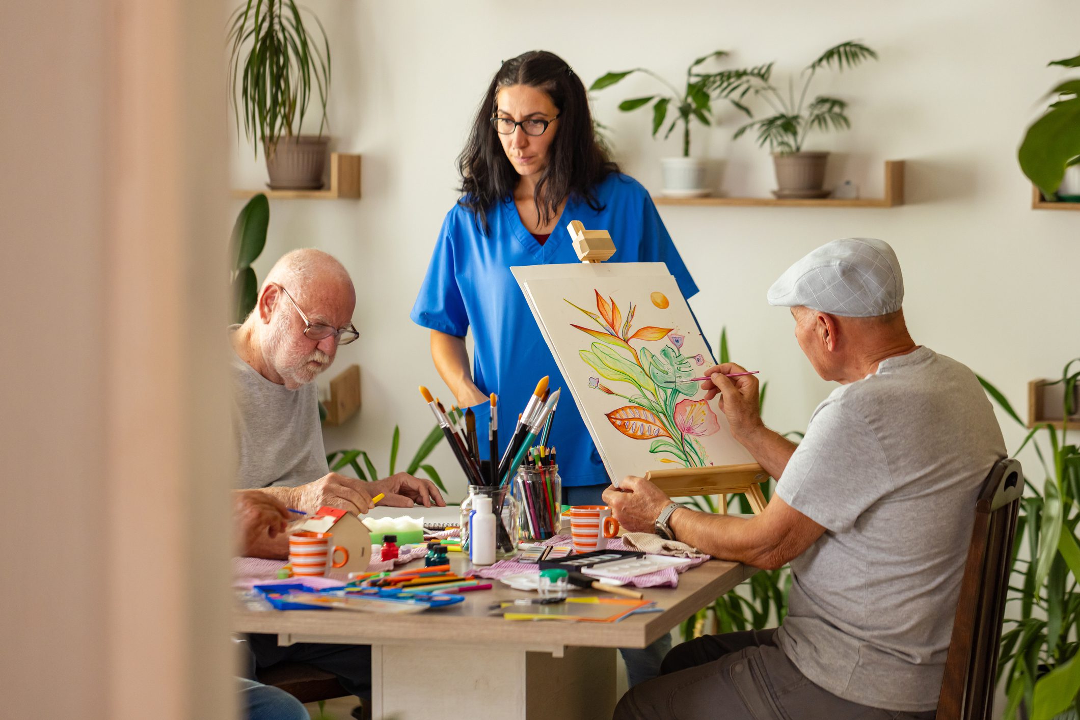 People painting at a table with instructor.