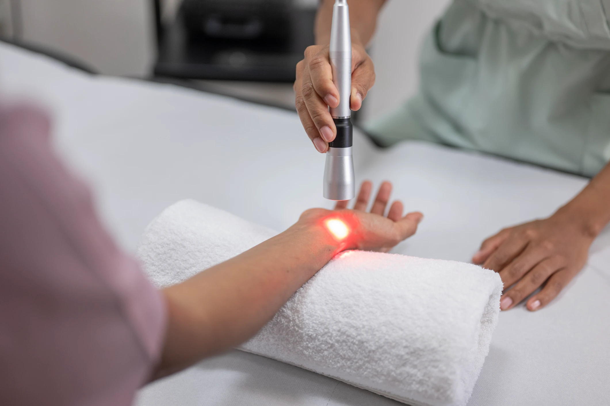 Laser therapy on arm with towel support.