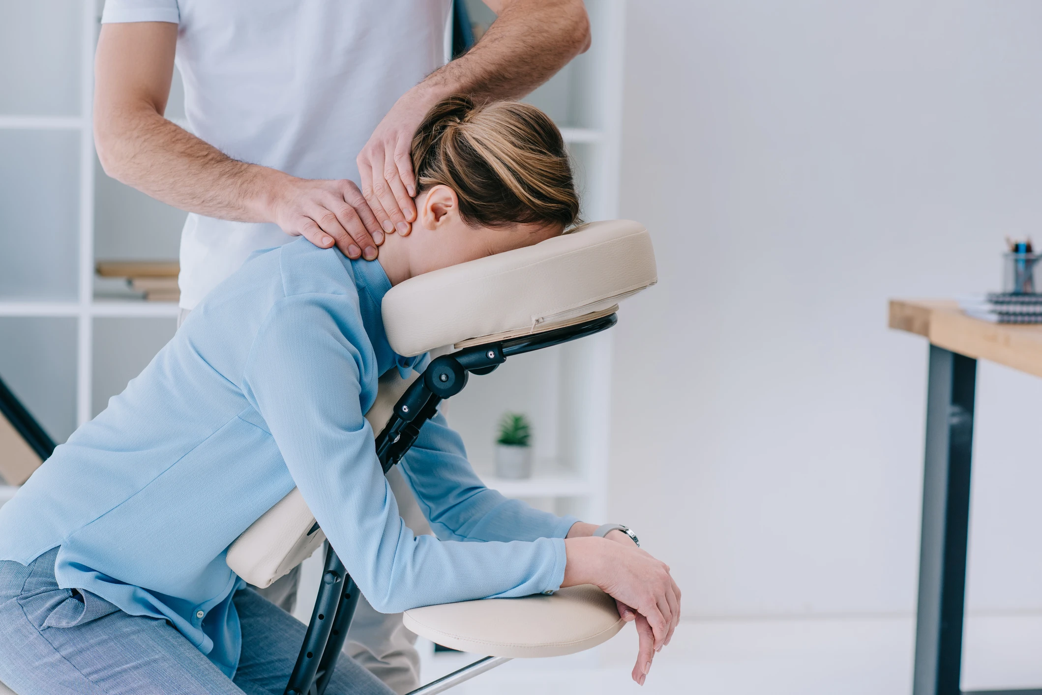 Person receiving neck massage on chair.