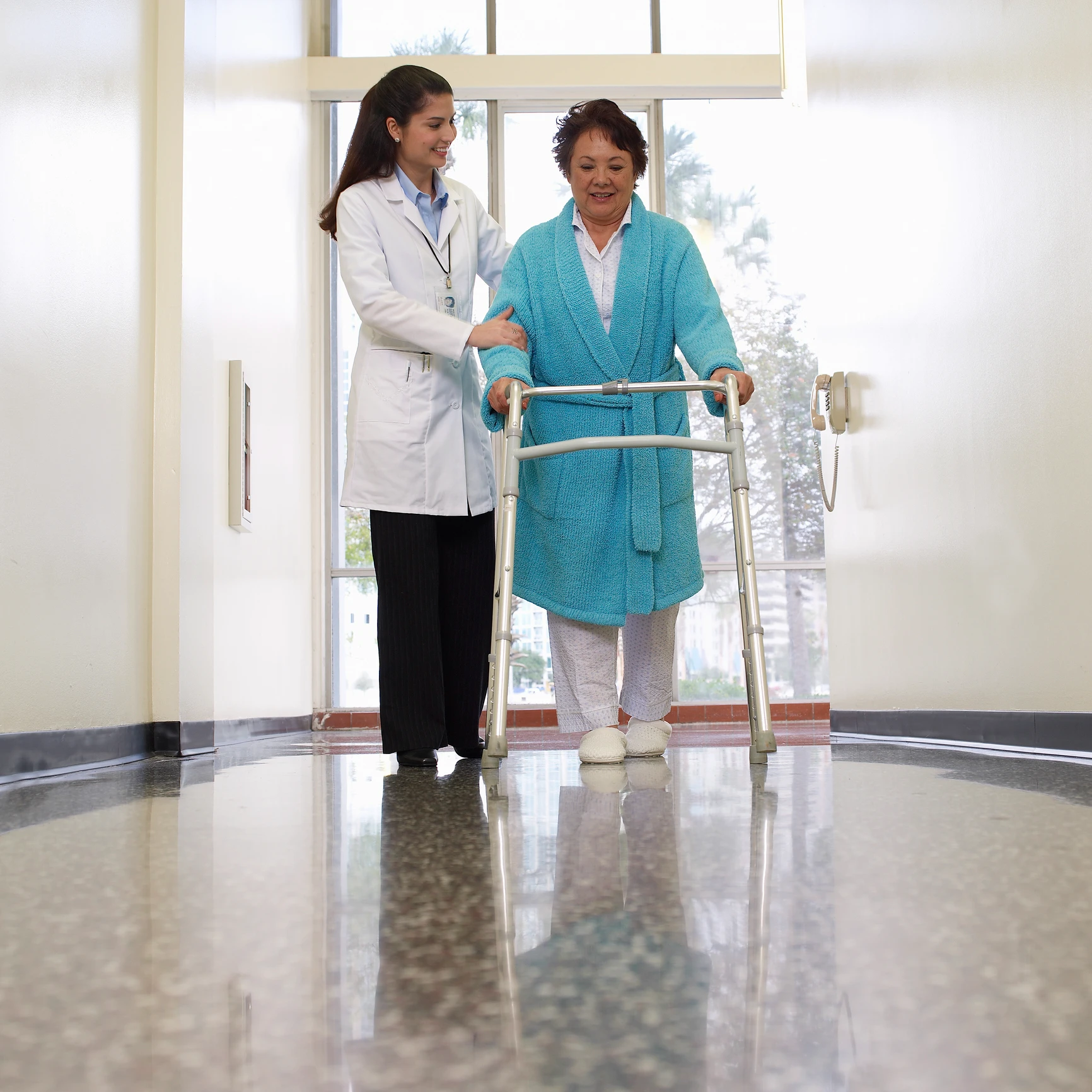 Doctor assisting elderly woman with walker.