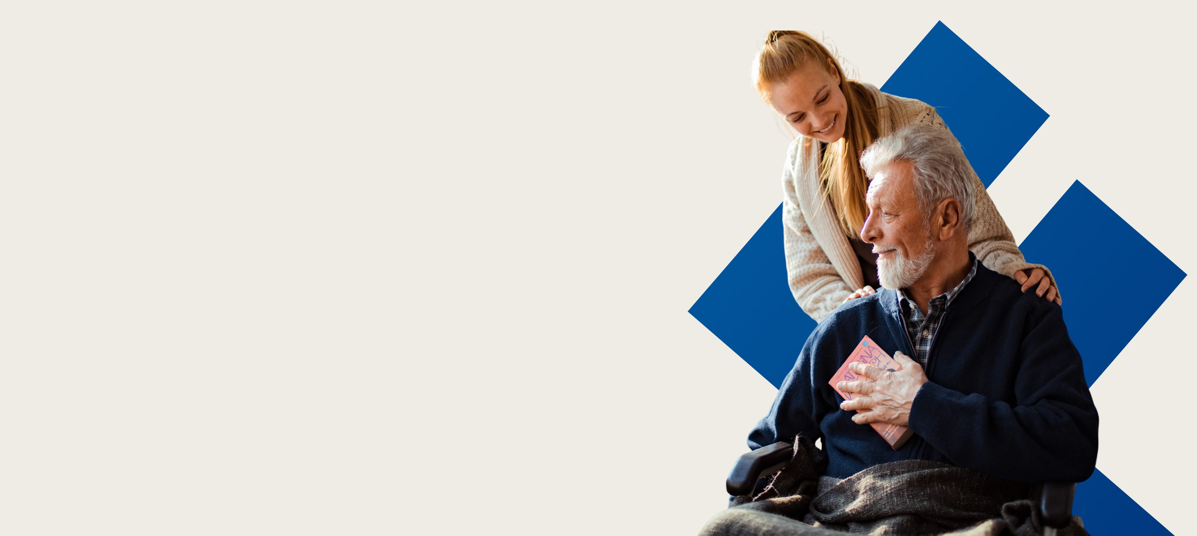 Elderly man in wheelchair with caregiver smiling.