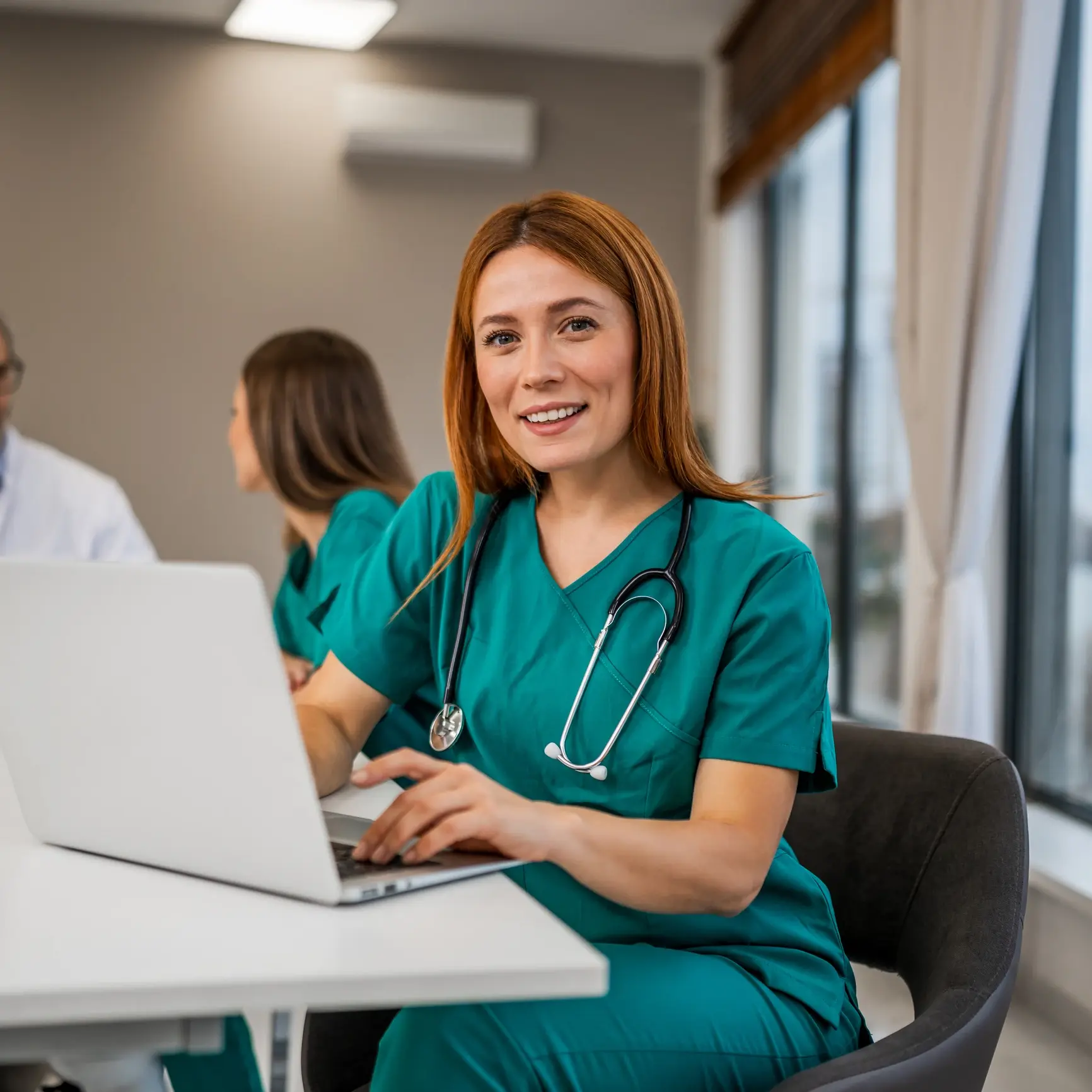 Smiling nurse working on a laptop.